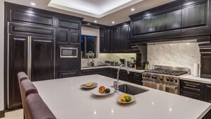 Una cucina moderna con mobili scuri, una grande isola con frutta, un piano cottura e un lavello.