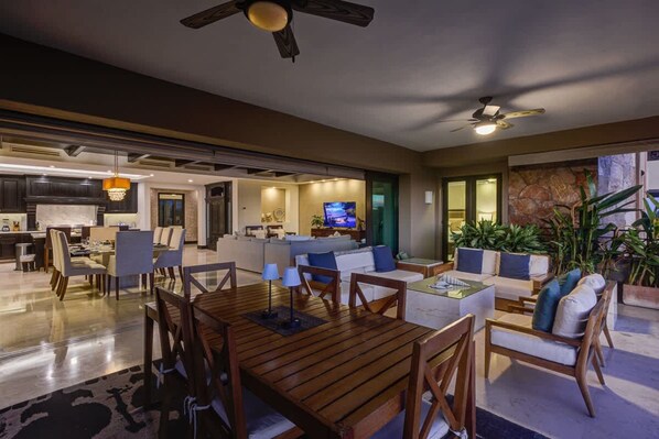 A spacious living area with a wooden dining table, comfortable seating, and a television in the background. - HDM 1205 By Owner Hacienda de Mita Beach Access (San Marcos)