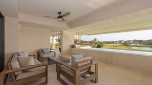 A balcony with wooden furniture, a ceiling fan, and a view of a river and greenery. - Encanto 822 by Owner Luxury Sunset Getaway Punta Mita (Punta de Mita)