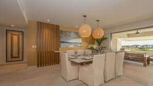 A dining area with a large table set for six, surrounded by cushioned chairs, with pendant lights above. - Encanto 822 by Owner Luxury Sunset Getaway Punta Mita (Punta de Mita)