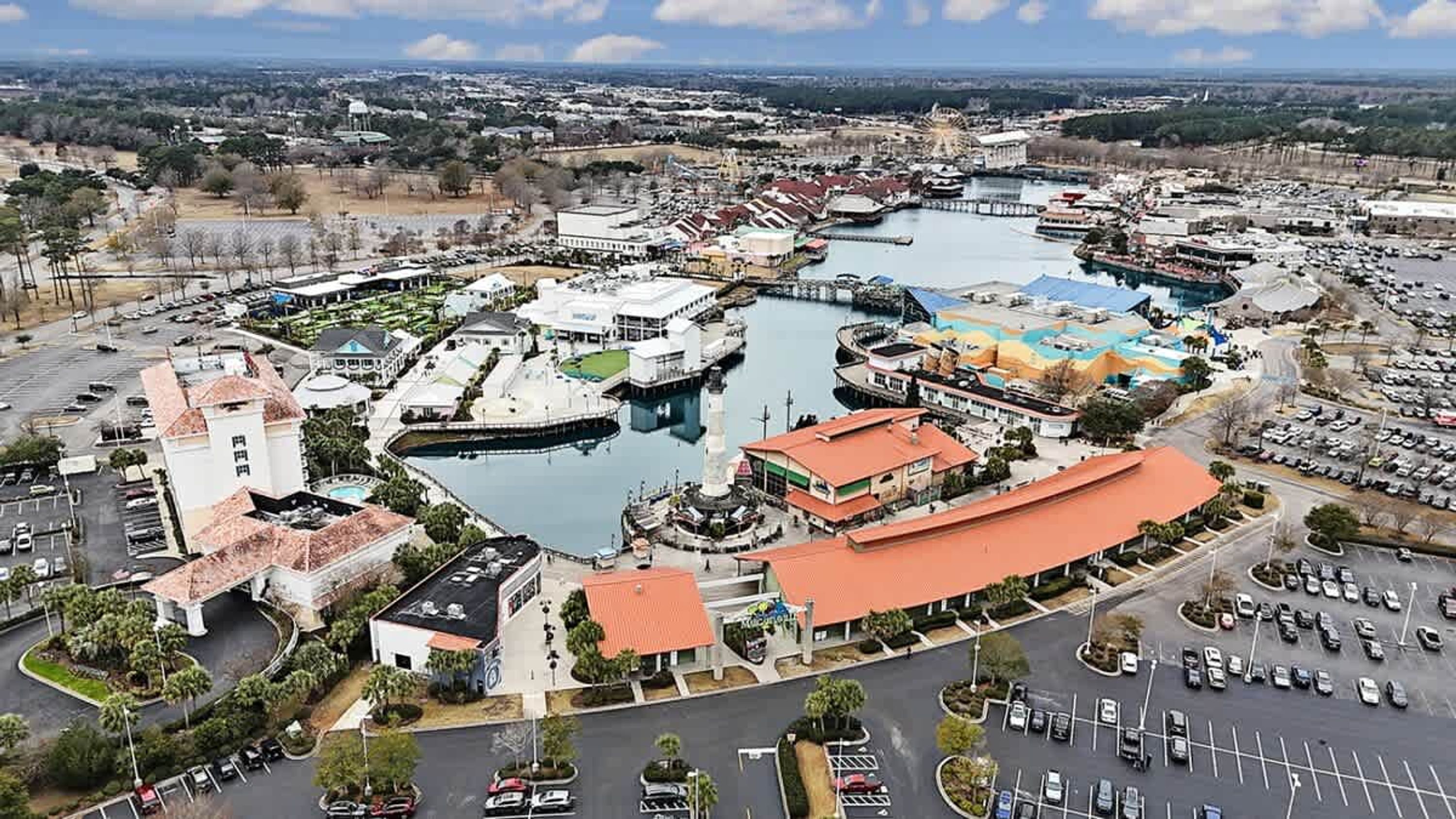 Luftaufnahme eines Wasseruferbereichs mit Gebäuden, einer Marina und einer großen Wasserfläche.