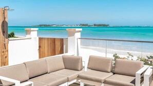 A balcony with two beige sofas and a wooden gate. - 2 Bed Condo at ONE Cable Beach With Balcony (Nassau)