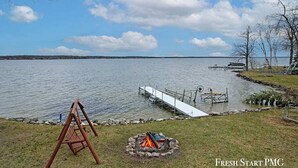 Vista para o lago com um cais, baloiço e uma lareira.