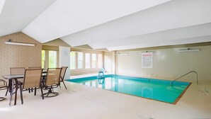 Una piscina interior amb una taula i cadires, una paret de maó i un cartell al mur.