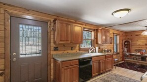 Una cocina de estilo cabaña de madera con lavavajillas incorporado, armarios de madera y un ventanal grande.