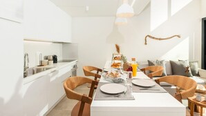A modern kitchen with white cabinetry, a dining table set with plates, glasses, and a fruit basket.