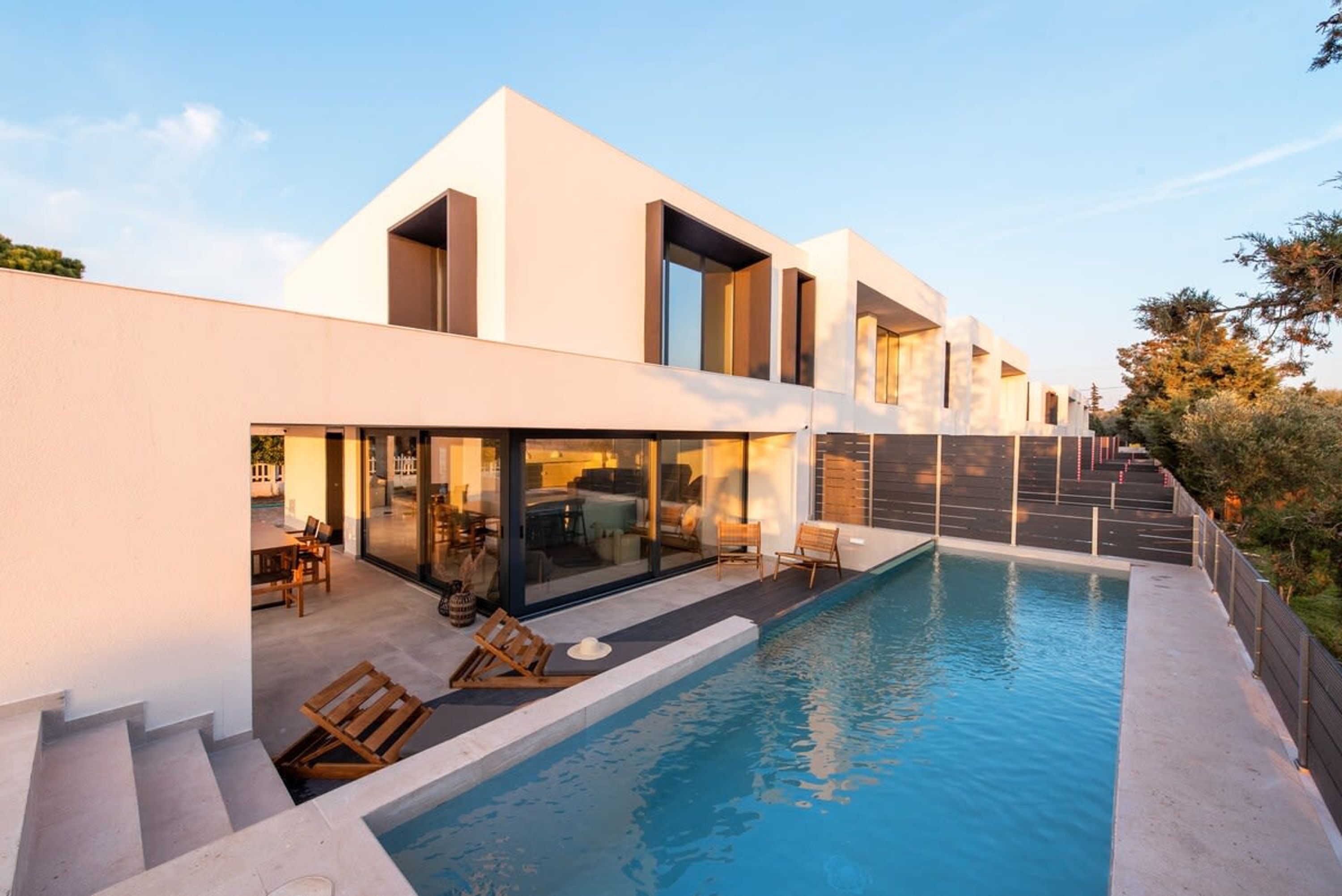 A modern house with a swimming pool, large windows, and a patio area.