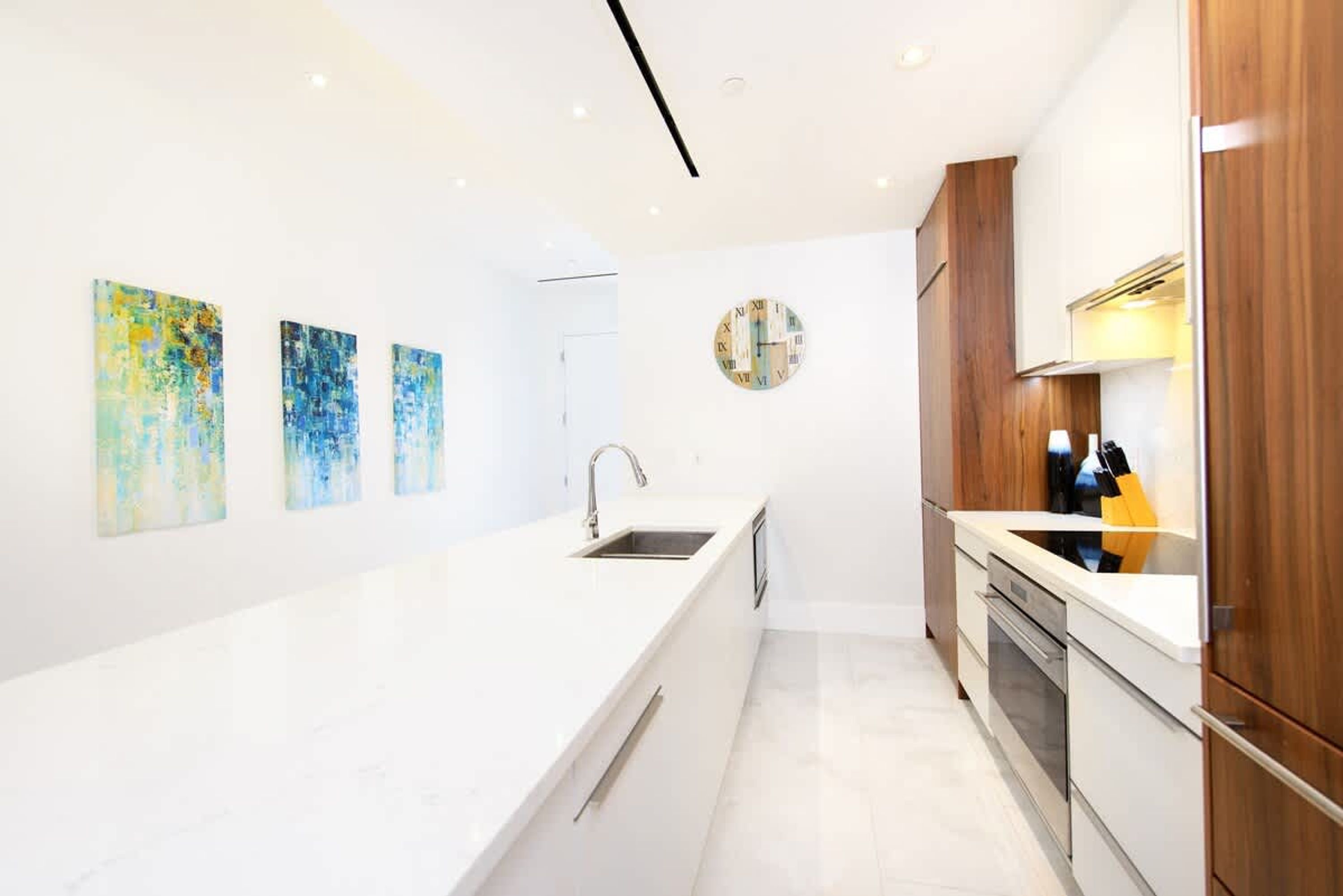 A modern kitchen with a white countertop, wooden cabinets, and a built-in oven.