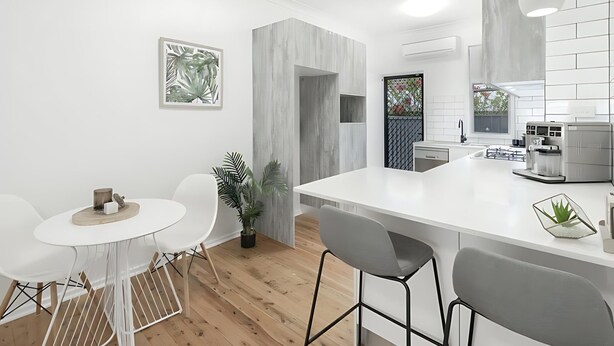 Une cuisine moderne avec des meubles blancs, un îlot central et des tabourets de bar.