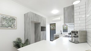 Une cuisine moderne avec des plans de travail blancs, des meubles de rangement gris et une machine à café intégrée.