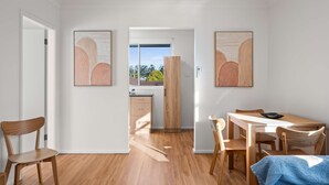 Eine moderne Küche mit Holzausstattung, einem Essbereich mit Tisch und Stühlen sowie Kunstwerken an den Wänden.