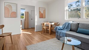 Ein modernes Wohnzimmer mit einer Couch, einem Glastisch und einem Essbereich mit Tisch und Stühlen.