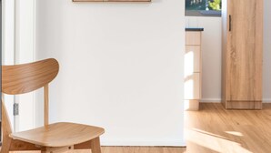 Ein modernes Interieur mit einem Holzstuhl, einem Holzkasten und einem gerahmten Kunstwerk an der Wand.