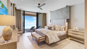 A modern bedroom with a large bed, a desk, a chair, and a view of the outdoors.