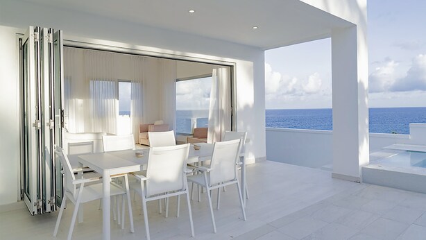 A modern, open-plan living area with a large sliding glass door leading to a balcony overlooking the sea. - Lilypad Luxurious Cliffside Villa With Stunning Sea Views (Ocean City)
