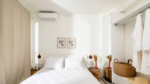 A modern bedroom with a large bed, bedside tables, a mirror, and a bathroom with a towel rack.