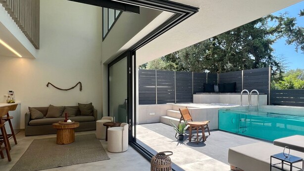 A modern outdoor living area with a pool, seating, and a staircase leading to an upper level.