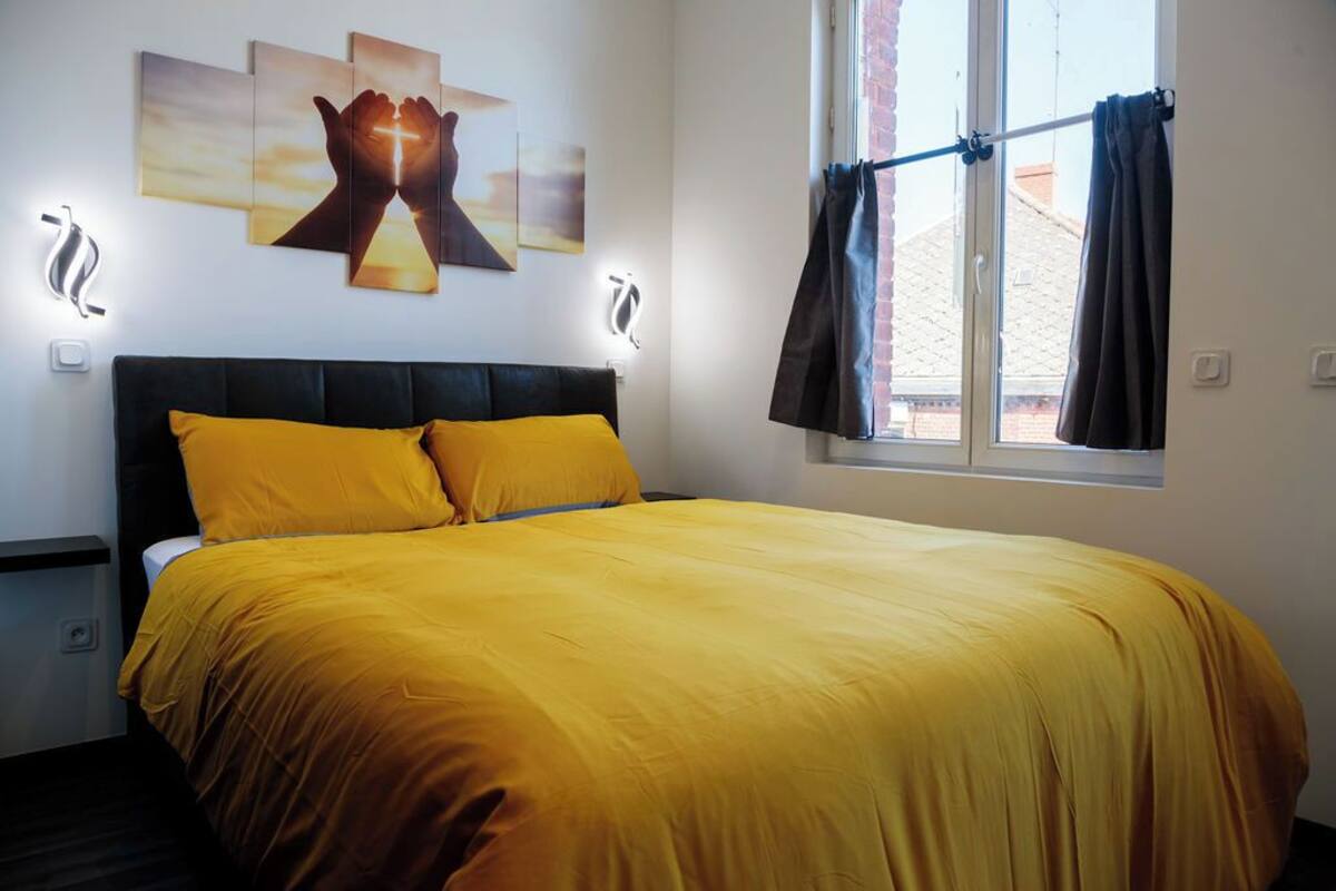 Een slaapkamer met een groot bed, een raam met gordijnen en wanddecoratie.