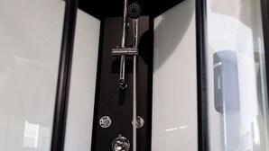 A glass-enclosed shower with a handheld showerhead and multiple control knobs. - SEE - Gare de Marly (Valenciennes)