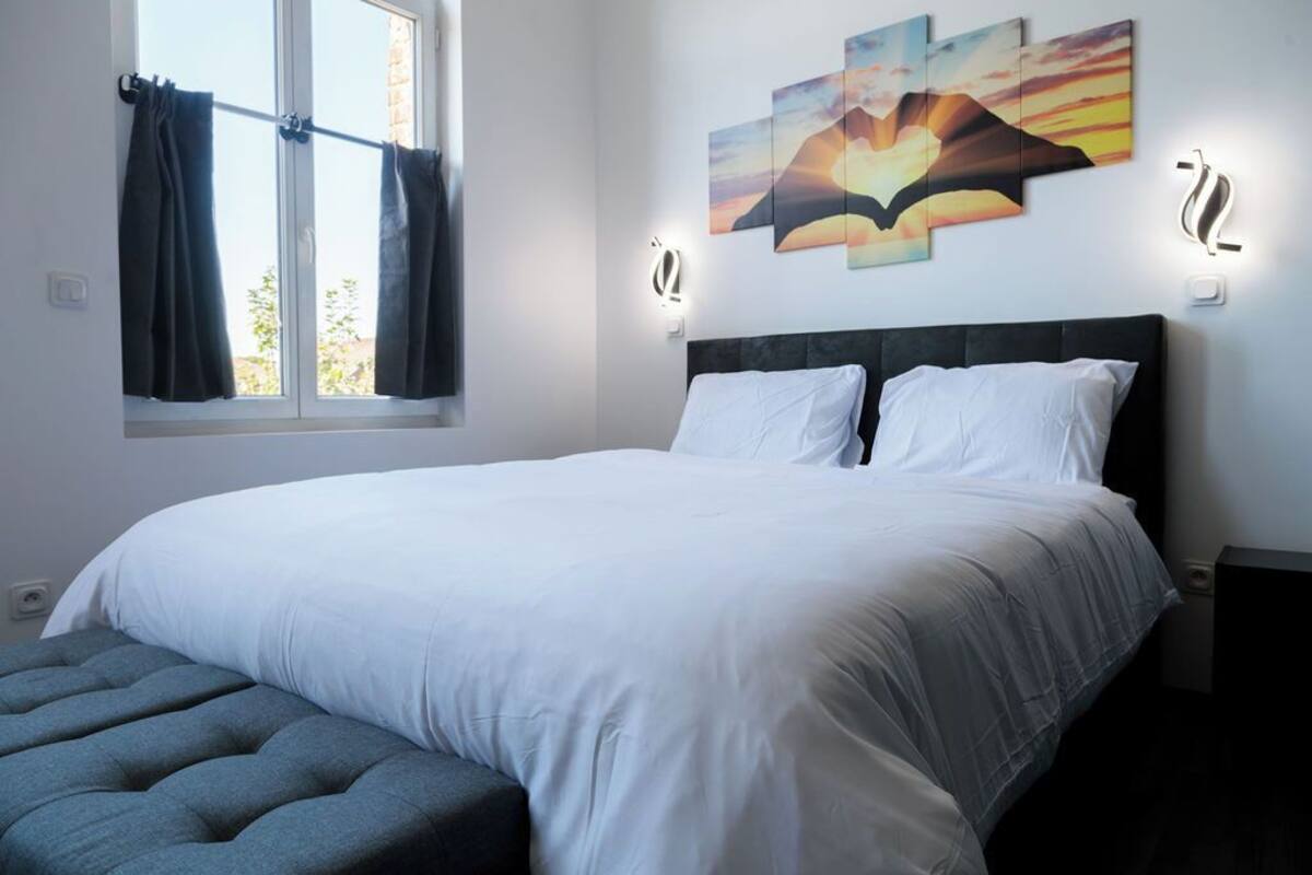 Een slaapkamer met een groot bed, een raam met gordijnen en wandlampen.