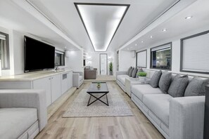 A modern living room with a flat-screen TV, a coffee table, and a sofa. - 7744 Ranch Entire Resort (Austin)