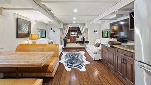 Un intérieur moderne comprenant un coin repas, des canapés, un téléviseur et une cuisine.