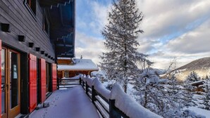 Un edificio de madera cubierto de nieve con un corredor techado y un árbol nevado.