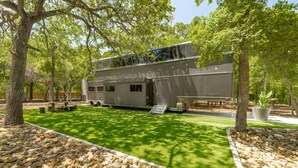 Un bâtiment moderne doté d’un toit plat, entouré d’une pelouse bien entretenue et de chemins en pierre.