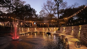 Une cour avec une fontaine, des murs en pierre et des guirlandes lumineuses.