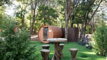 A rustic outdoor setting with a wooden barrel structure, a round table, and several tree stump stools.