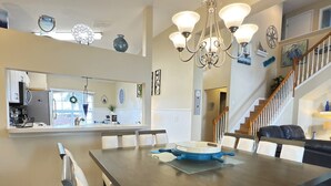 A modern kitchen with a dining area, a chandelier, and a staircase. - Near Disney Villa 3 bd Private Pool (Davenport)
