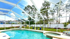A covered outdoor swimming pool with a hot tub, surrounded by a white fence and trees. - Near Disney Villa 3 bd Private Pool (Davenport)