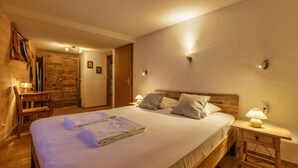 Una camera d'albergo con un letto grande, una testiera in legno, comodini con lampade e un armadio in legno.