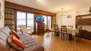 A cozy living room with a sofa, a television, and a dining area with a table and chairs. - Nevada 205 4 pax Central Apartment Garage (Riddes)
