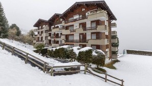 A multi-story building with balconies, surrounded by snow-covered trees and a wooden staircase. - Nevada 205 4 pax Central Apartment Garage (Riddes)