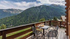 A wooden deck with a table and chairs overlooking a mountainous landscape. - El Paradiso - Luxury Chalet Sauna w Views (Riddes)
