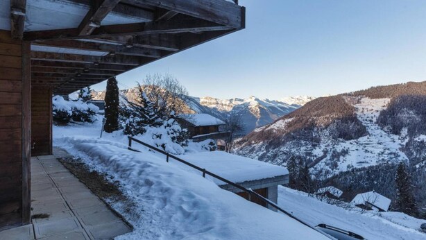 A wooden cabin with a snow-covered exterior, a wooden deck, and a view of snow-covered mountains. - El Paradiso - Luxury Chalet Sauna w Views (Riddes)