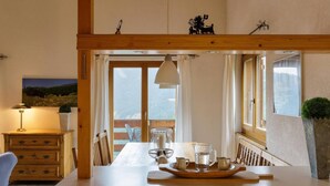 A dining area with a wooden table, chairs, a hanging lamp, and a view of the outdoors. - El Paradiso - Luxury Chalet Sauna w Views (Riddes)