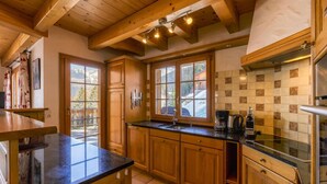 Una cucina con mobili in legno, un piano di lavoro nero e una finestra vista alberi.