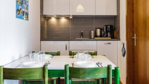 A dining area with a white table set for two, equipped with plates, cutlery, and glasses. - Belle Vue Apartment 423 (Riddes)