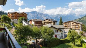 A mountain resort with multiple chalet-style buildings, a clear view of the mountains, and a well-maintained garden area. - Belle Vue Apartment 423 (Riddes)