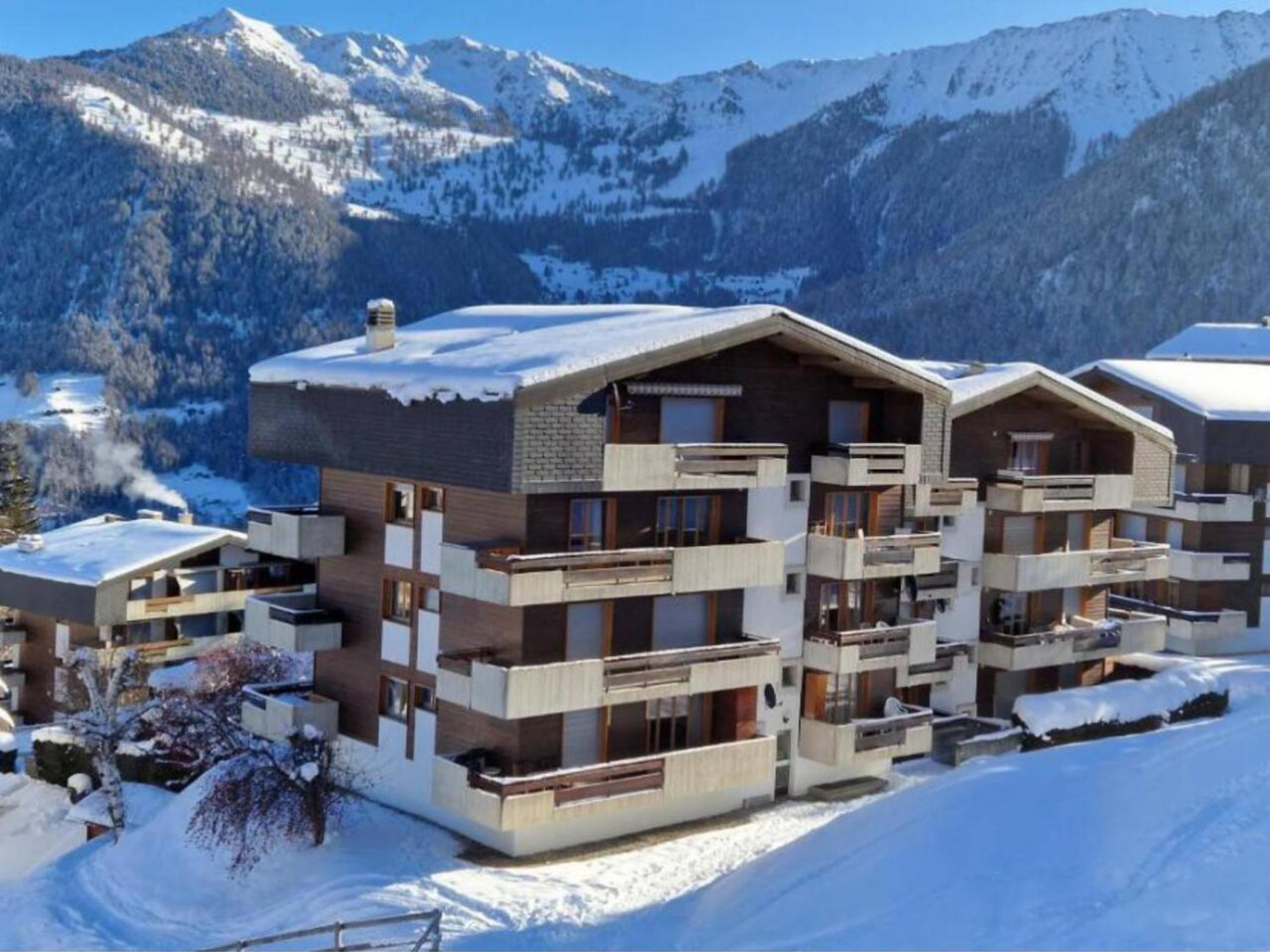 Een hotel met meerdere verdiepingen en balkons, gelegen tegen een besneeuwde berg.