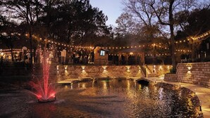 A courtyard with a fountain, stone walls, and string lights. - Studio 7744 Ranch Austin Venue and Rentals (Austin)