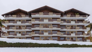 Een hotel met meerdere verdiepingen, balkons en een met sneeuw bedekte grond.