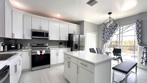 A modern kitchen with white cabinets, stainless steel appliances, and a large island with seating.
