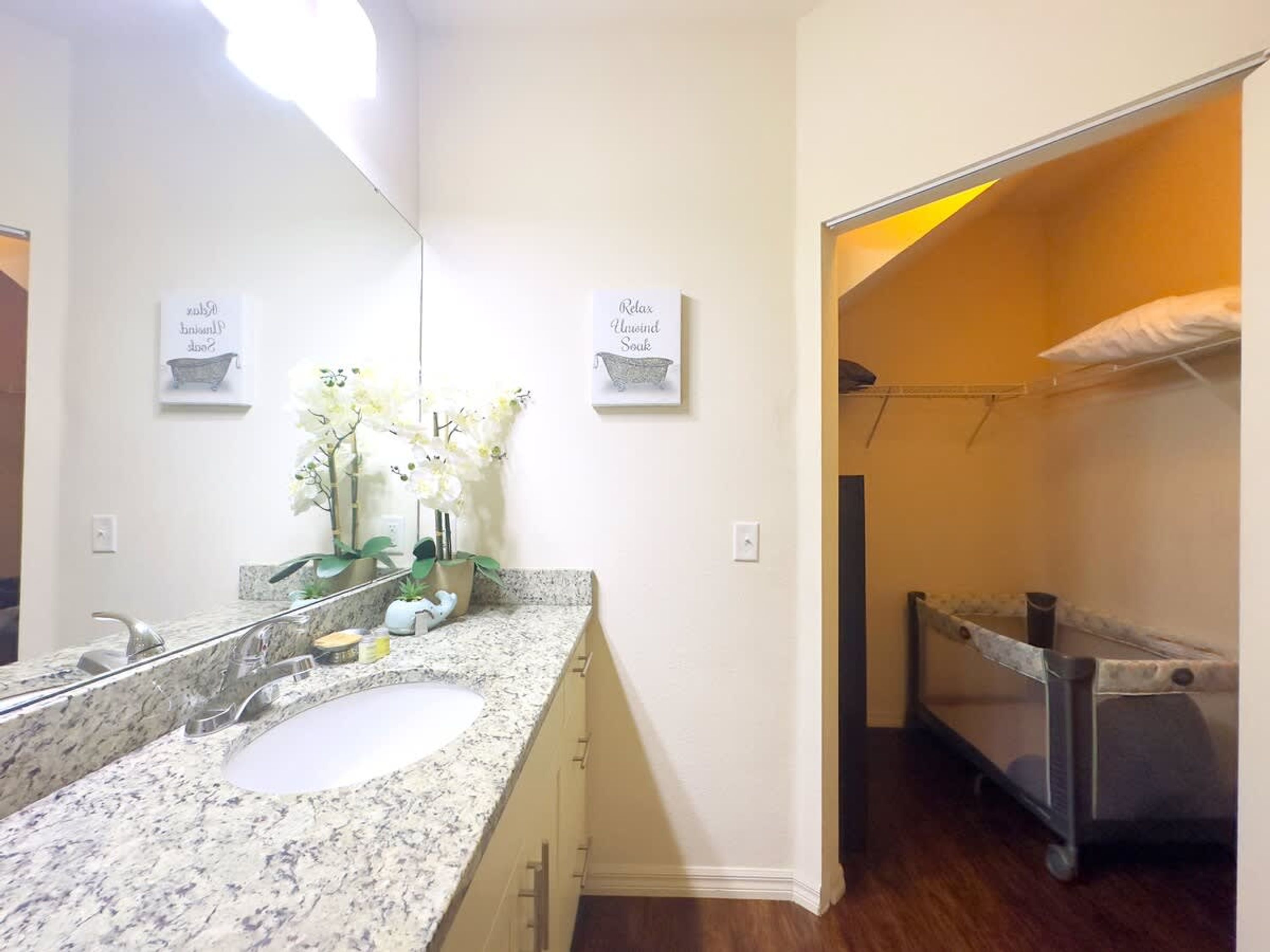 A bathroom with a granite countertop, a sink, a mirror, and a shower area with a towel rack.