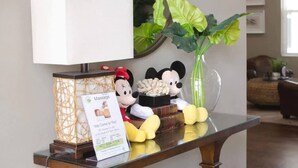 A reception desk with a massage advertisement, a lamp, a Mickey Mouse figurine, and a plant. - 4Bd Minions Themed Home Near Disney Sleeps 10 (Kissimmee)