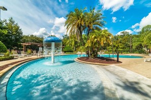 A swimming pool with a water fountain, surrounded by palm trees and lounge chairs. - 4Bd Minions Themed Home Near Disney Sleeps 10 (Kissimmee)