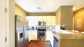 A modern kitchen with stainless steel appliances, a microwave, oven, and dishwasher. - 4Bd Minions Themed Home Near Disney Sleeps 10 (Kissimmee)