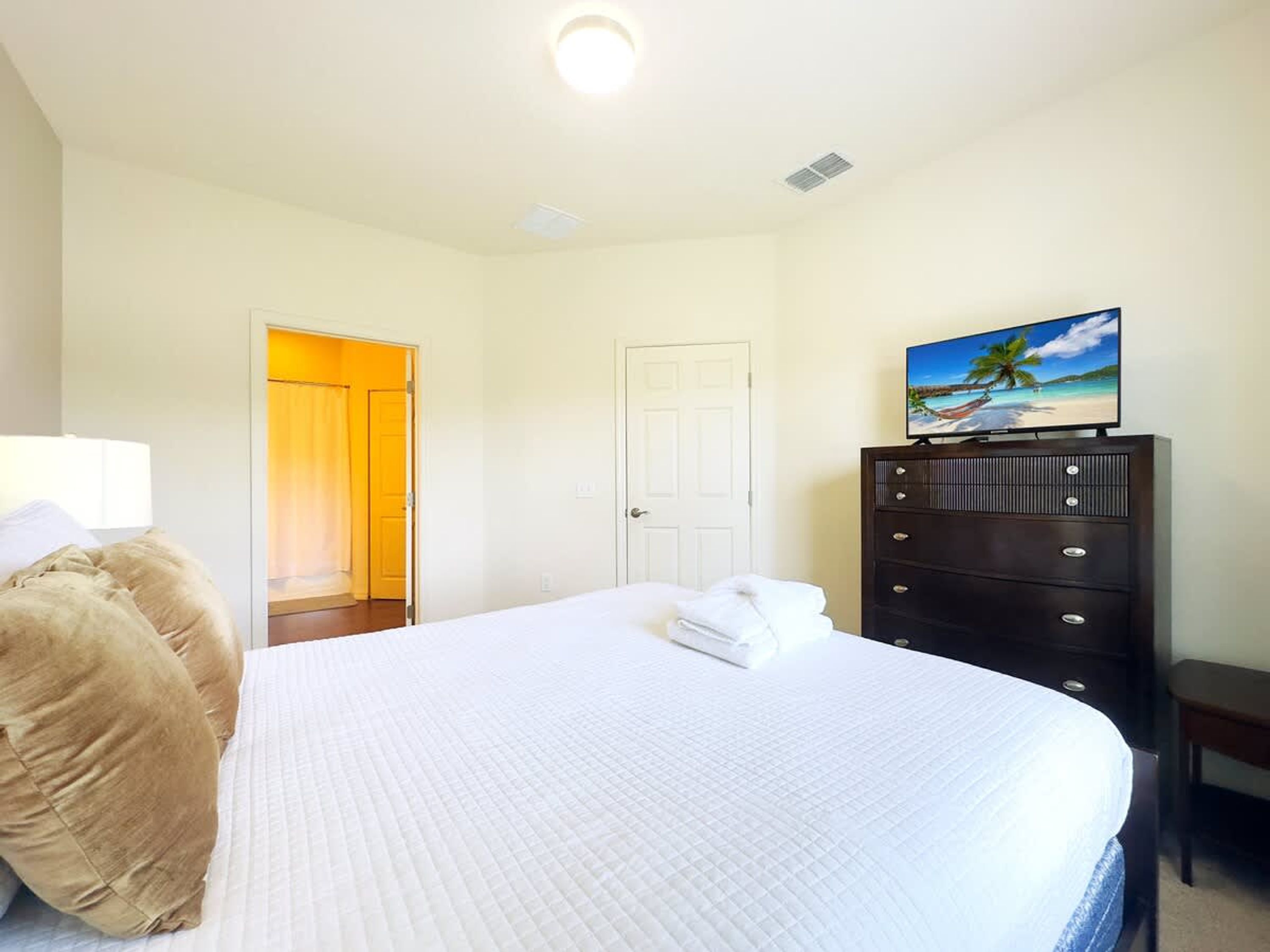 A bedroom with a bed, a dresser, a painting, and a door.